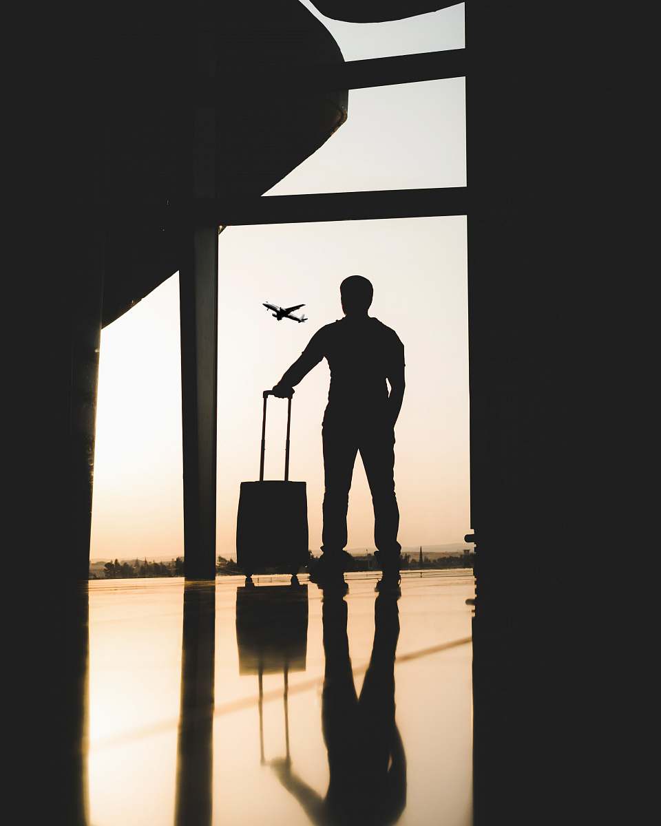 person silhouette of man holding luggage inside airport people