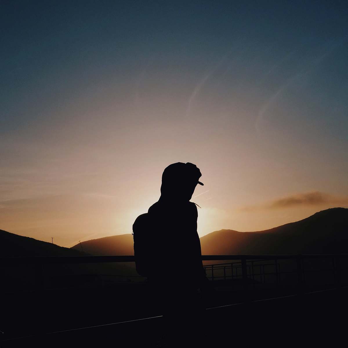 dawn silhouette of man leaning on rails dusk