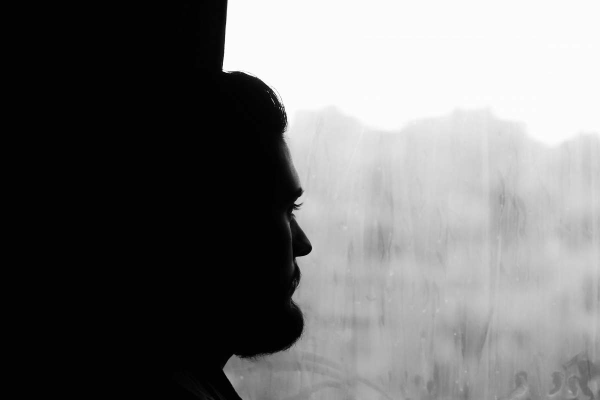 black-and-white silhouette of man near window grey