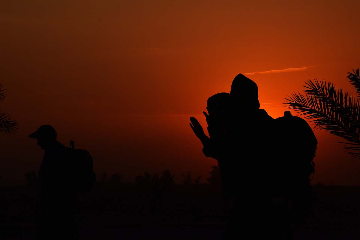 nature silhouette of man sitting on grass under brown sky during nighttime outdoors