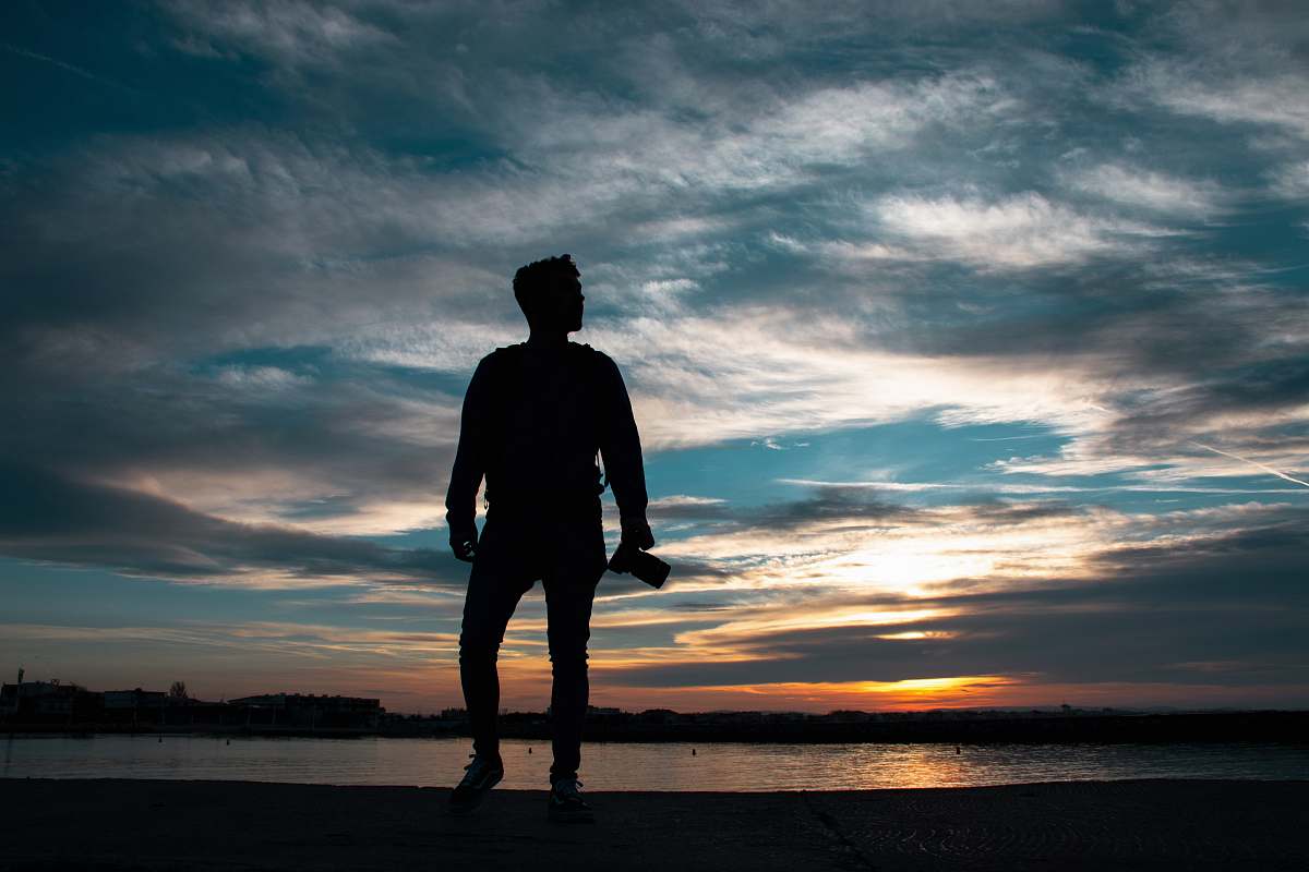 human silhouette of man standing holding camera person