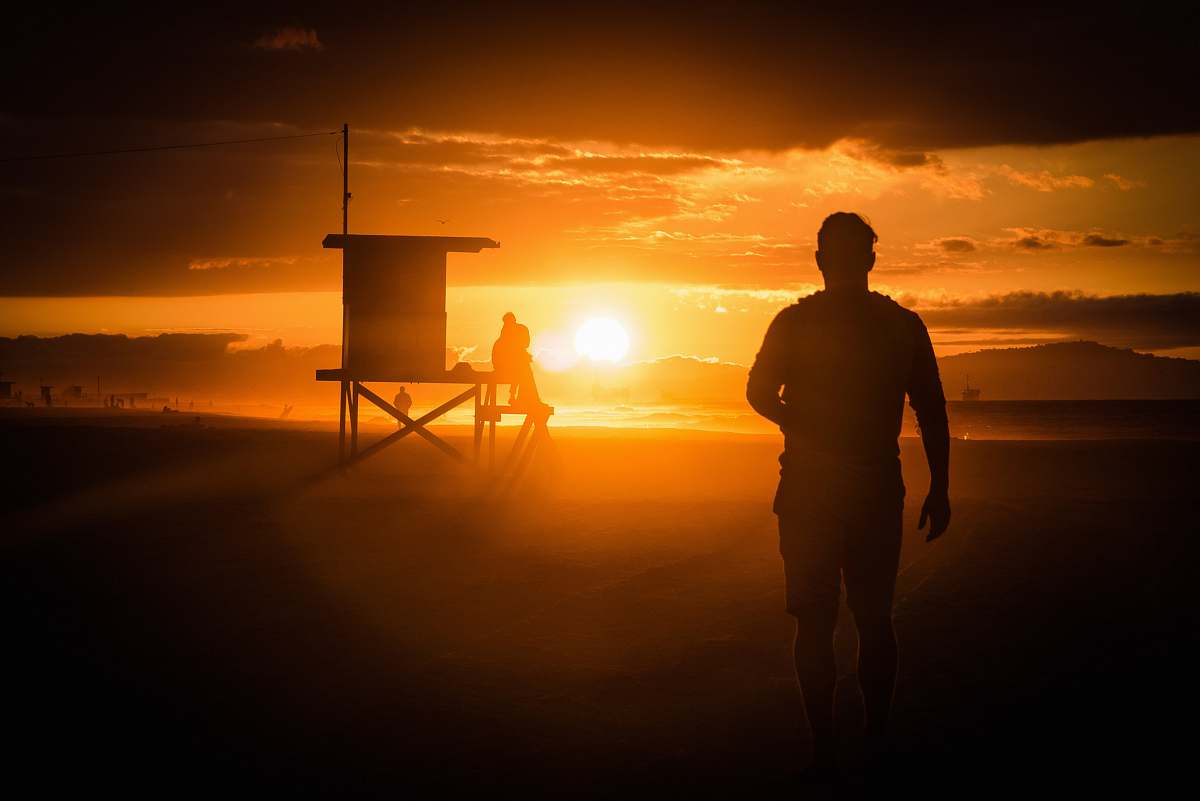 person silhouette of man standing near wooden shed during sunset newport beach