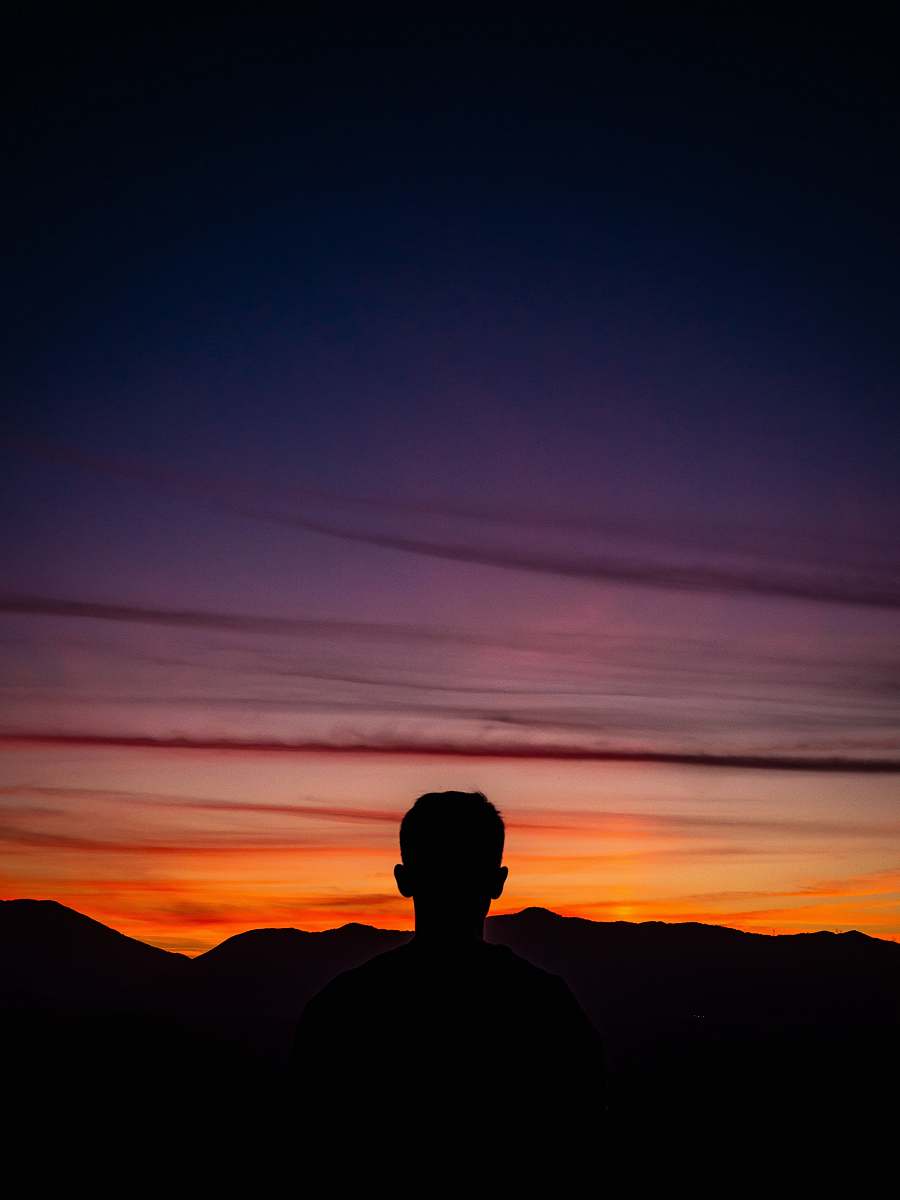 person silhouette of man standing with mountain on horizon human