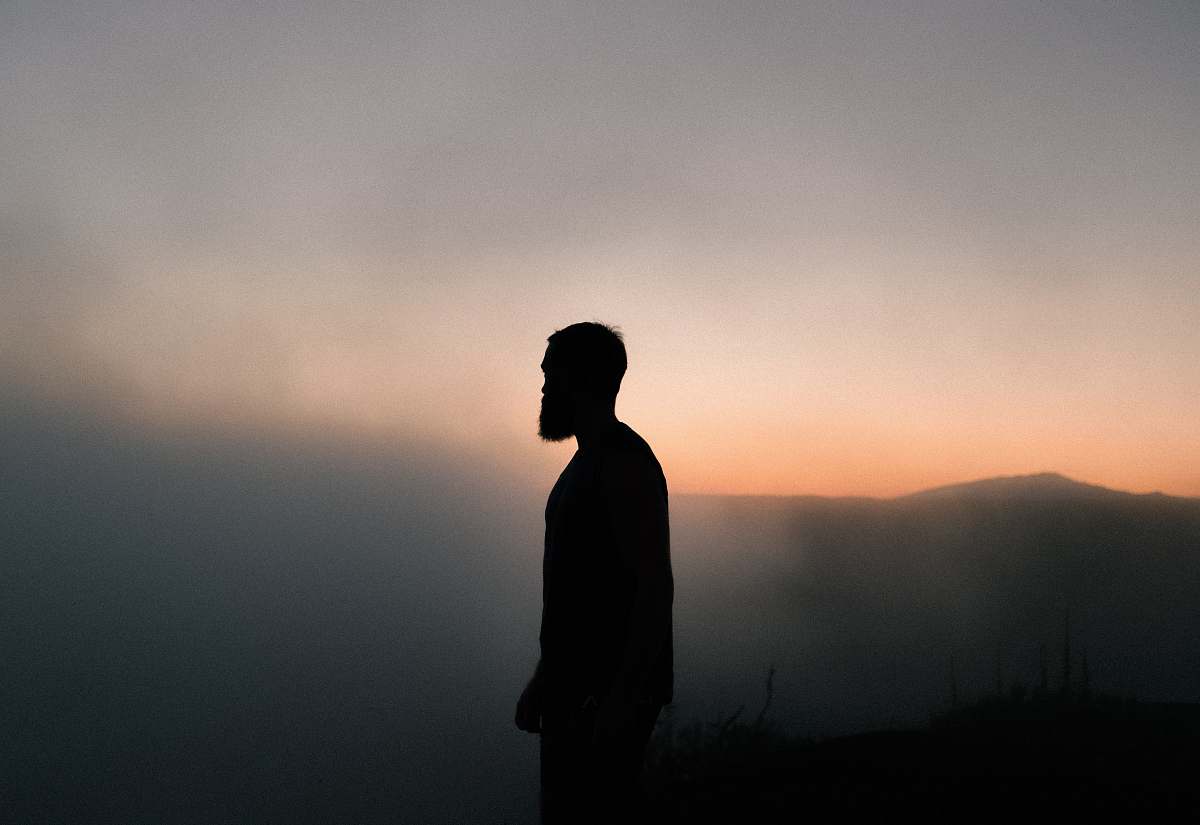 human silhouette of man surrounded with fog during golden hour person