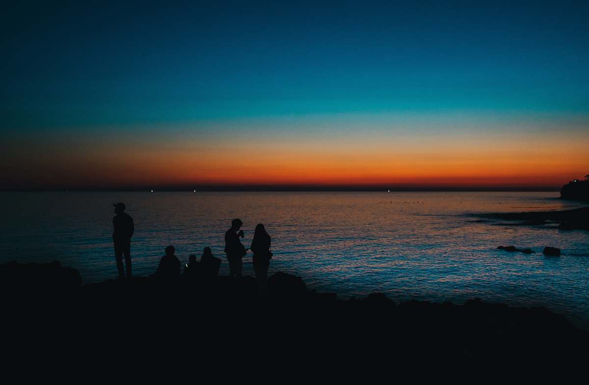 nature silhouette of people standing near body of water during golden hour human