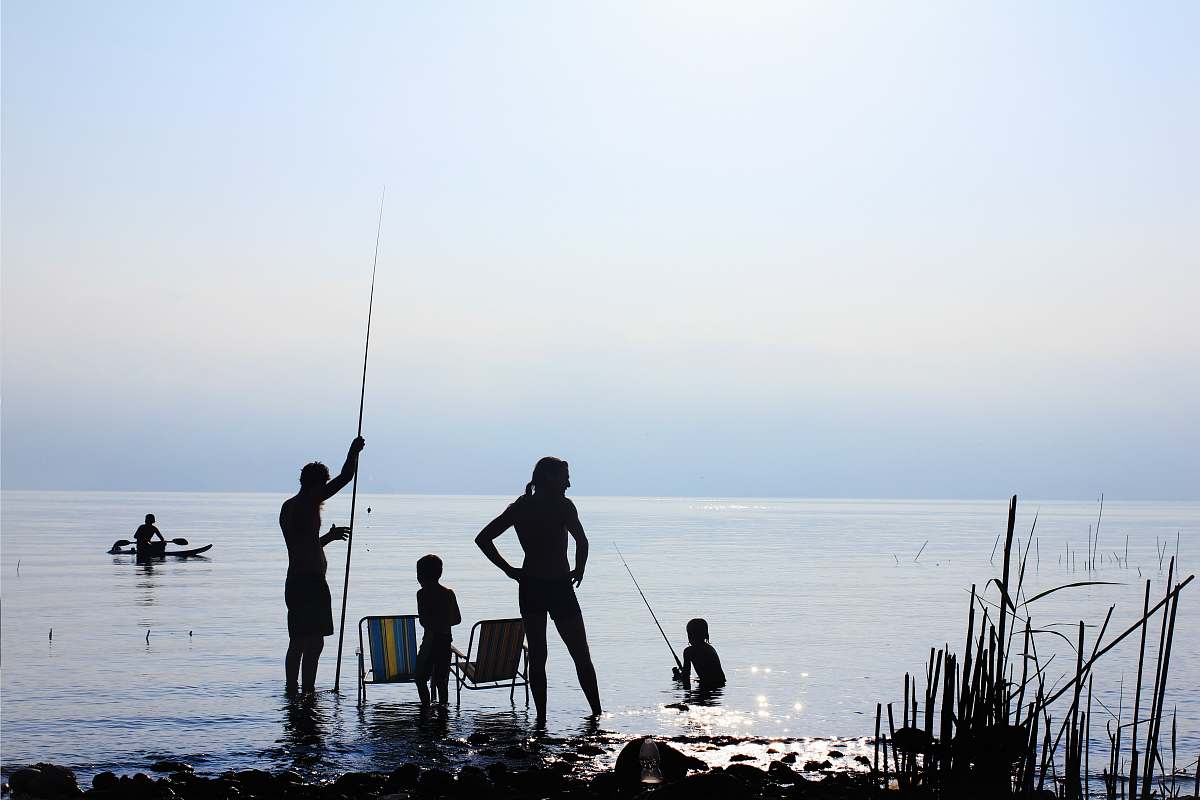 fishing silhouette of people standing on water during daytime family