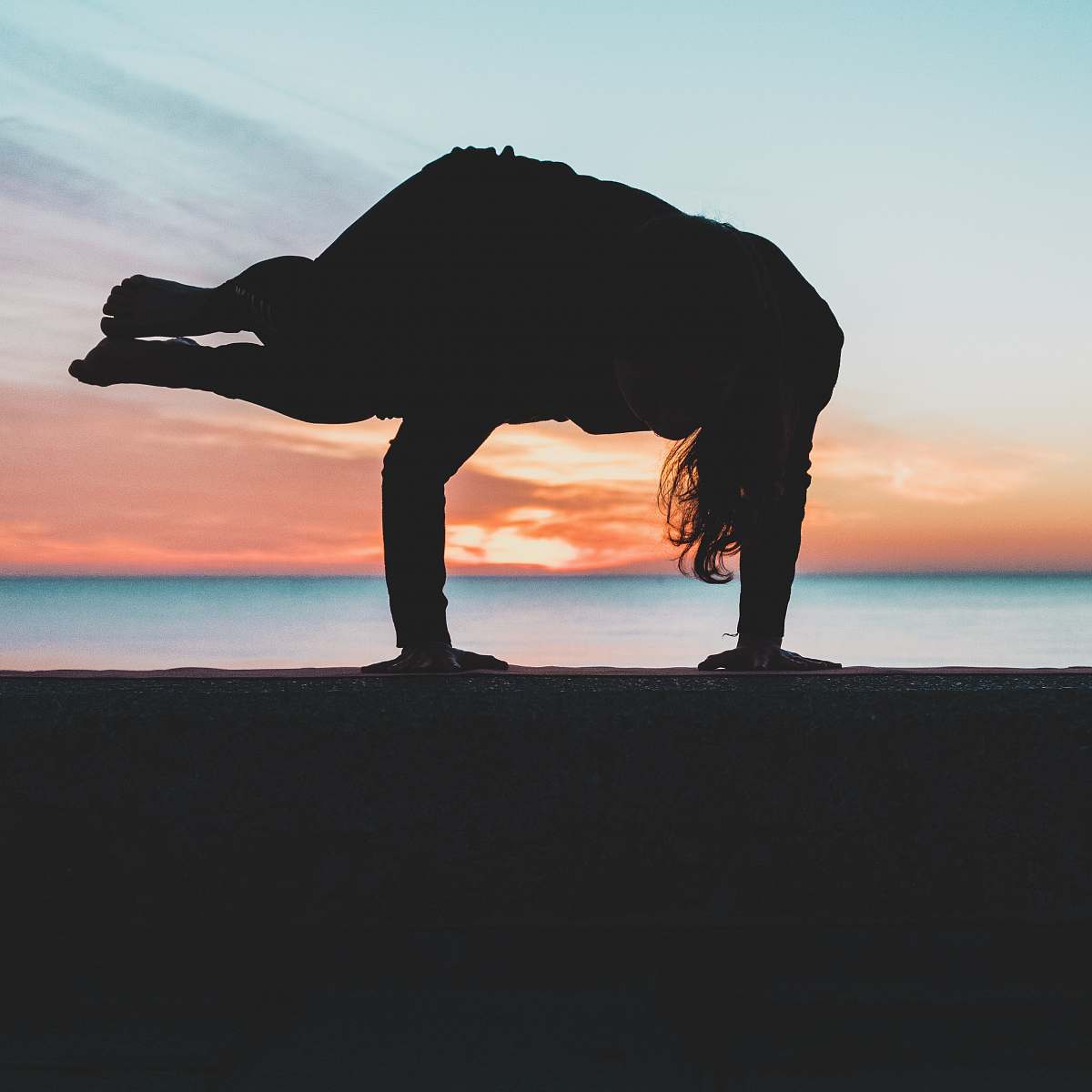 water silhouette of person doing hand stand shoreline