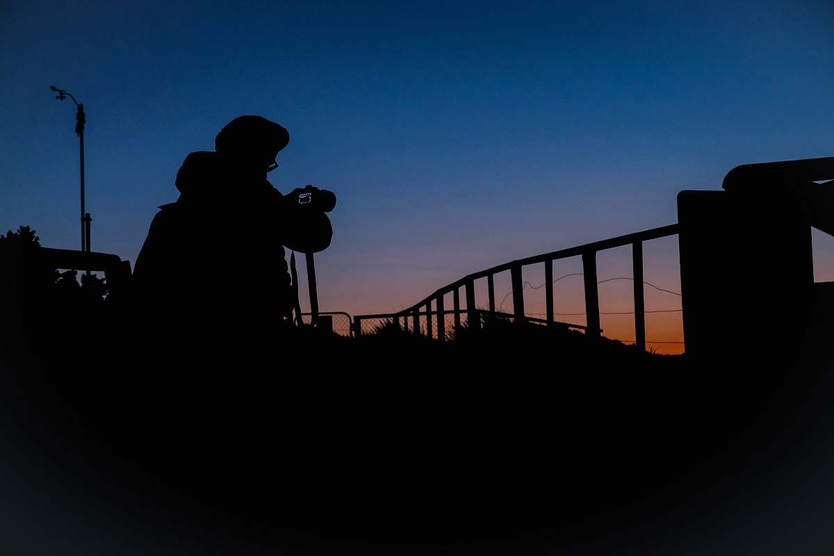 human silhouette of person holding DSRL camera railing