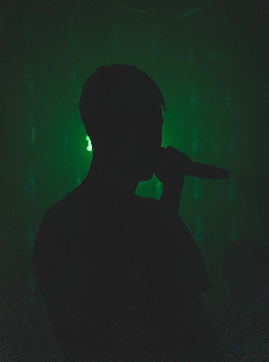 human silhouette of person holding microphone back