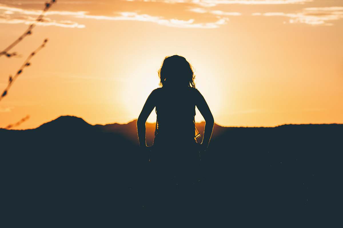 horizon silhouette of person looking at sunset oragne