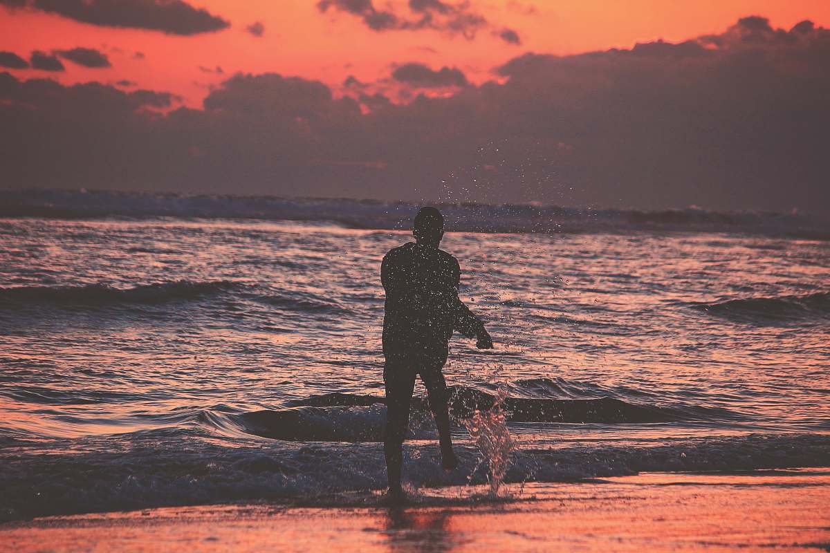 person silhouette of person on sea shore during golden hour human
