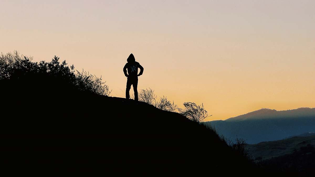 human silhouette of person on top of hill during golden hour person