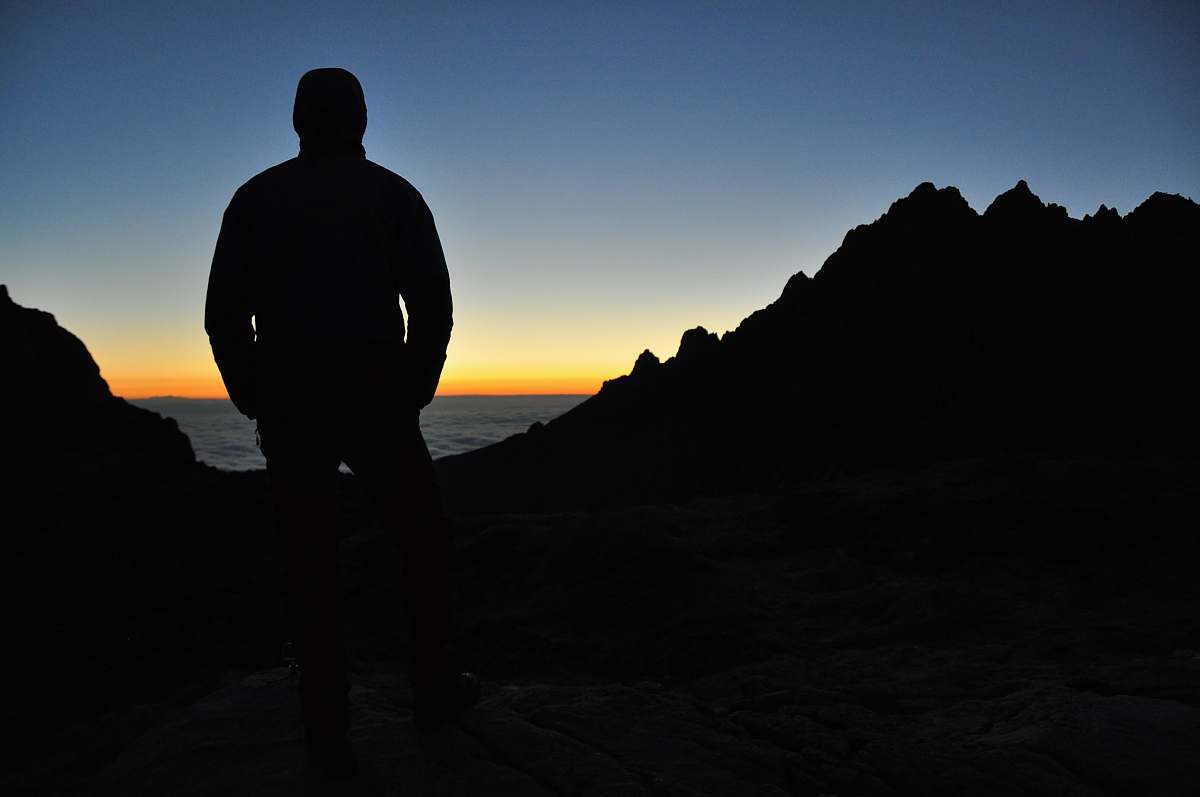 human silhouette of person on top of mountain under blue sky during orange sunset person