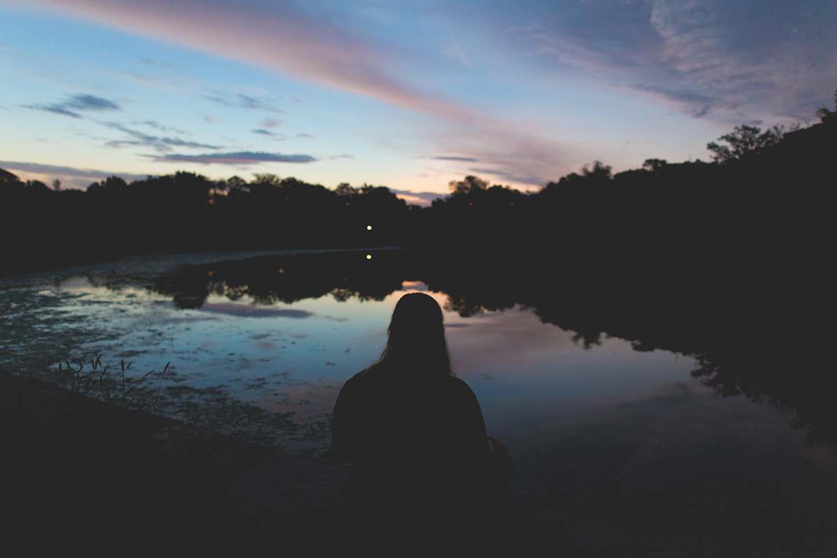 trees silhouette of person sitting near body of water sky