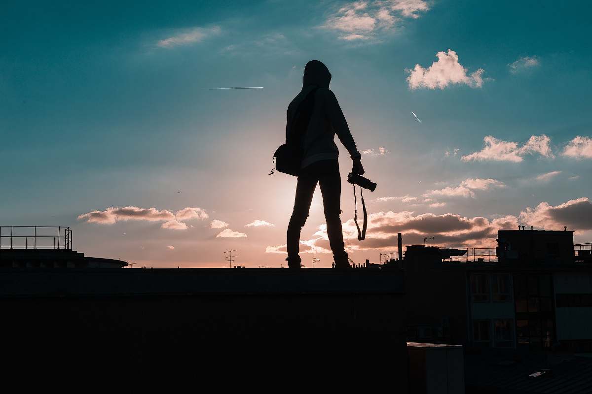 person silhouette of person standing and holding DSLR camera human