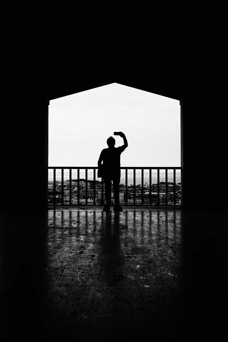 human silhouette of person standing beside metal fence black-and-white