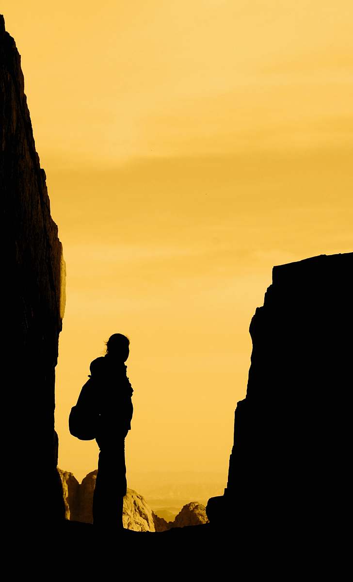 human silhouette of person standing in between rocks person