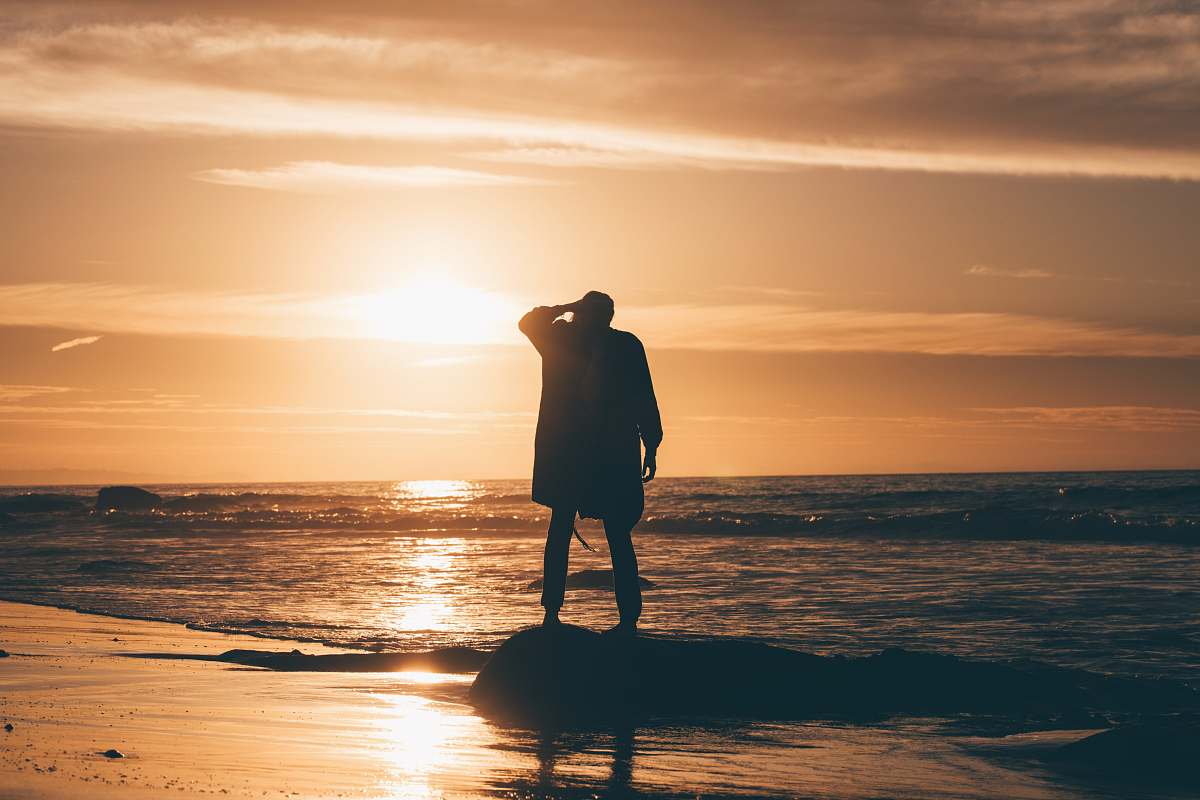 person silhouette of person standing on body of water beach