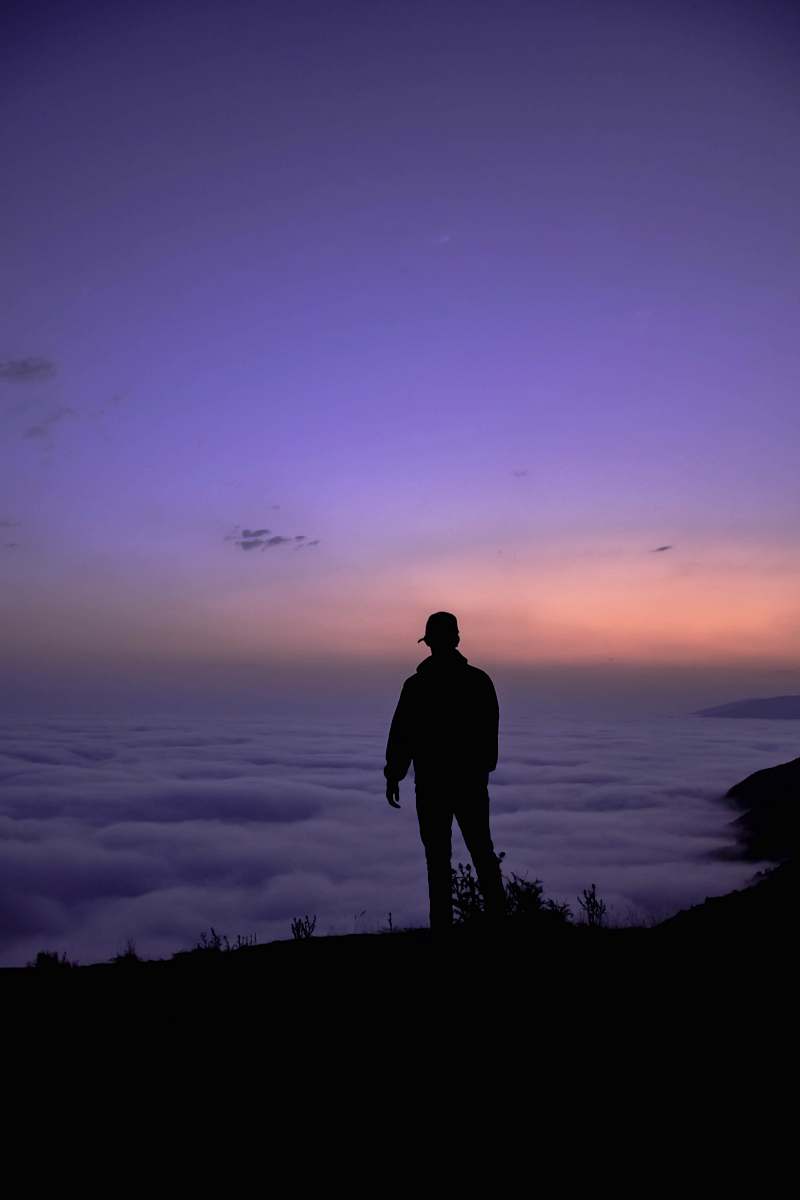 human silhouette of person standing on cliff during golden hour nature