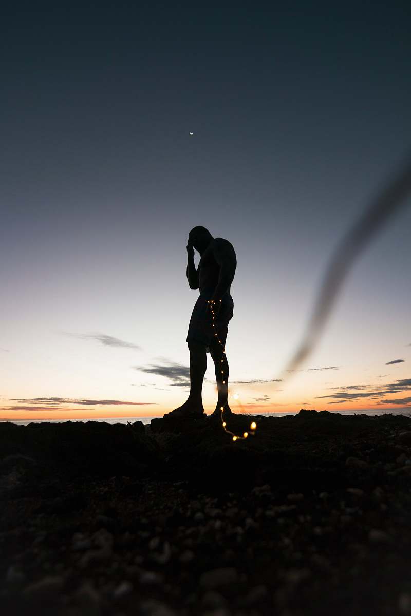 human silhouette of person standing on rock during sunset person