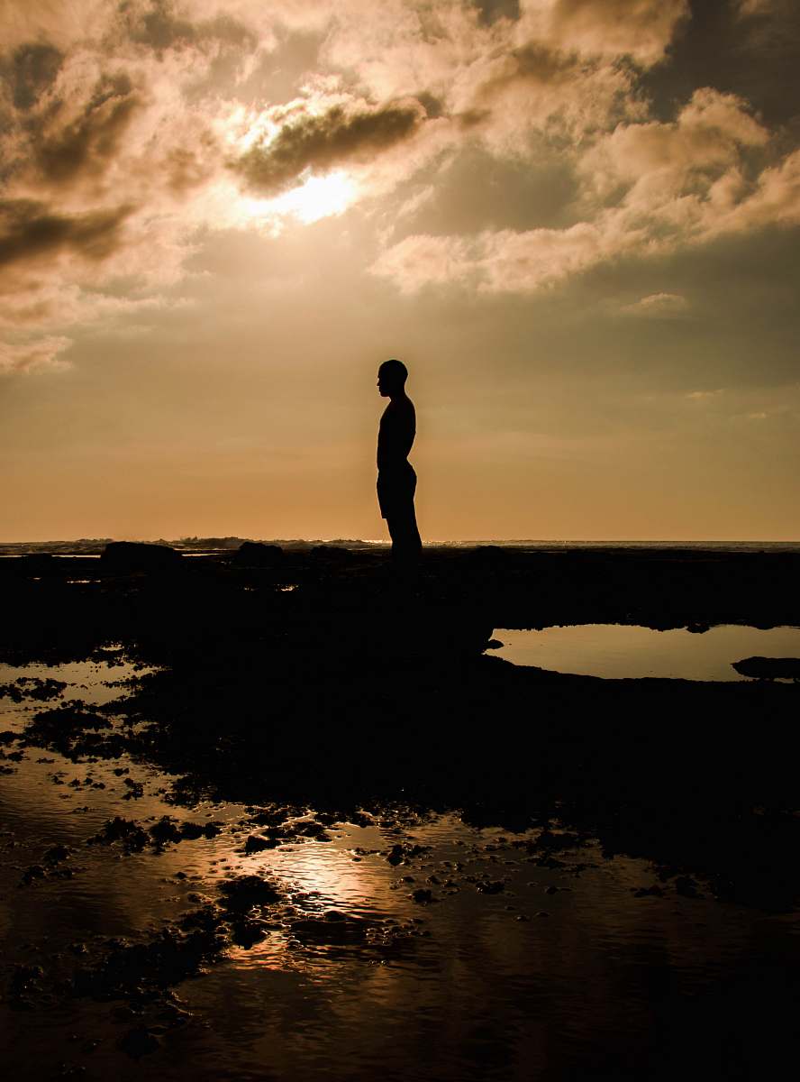 flare silhouette of person standing on rock light