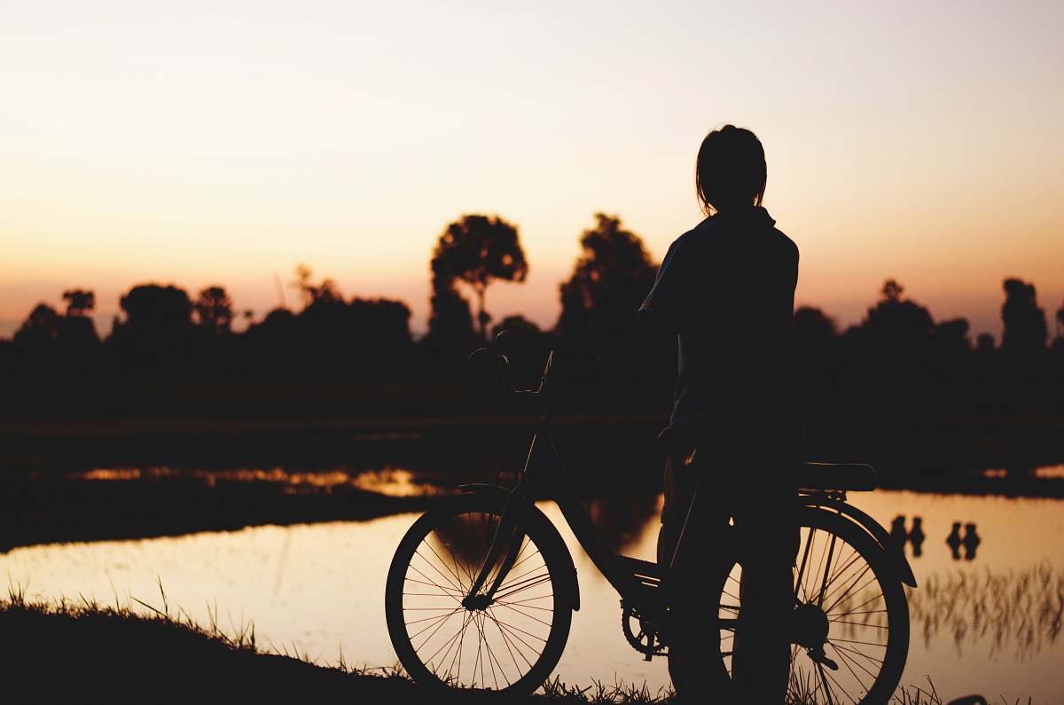 person silhouette of person with bicycle near body of water bicycle