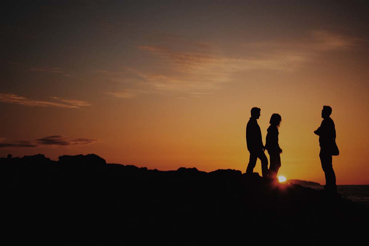 brown silhouette of two men and one woman on mountain laguna beach