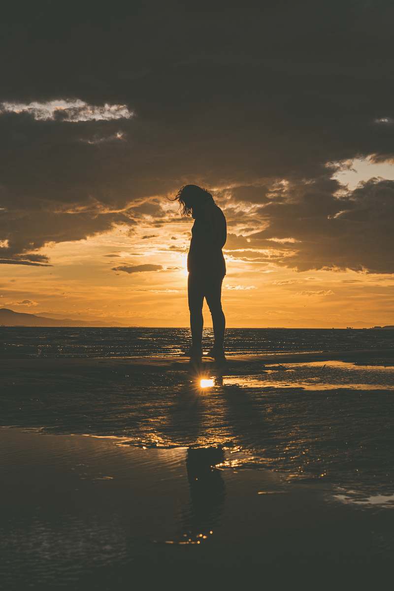 flare silhouette of woman near the body of water light