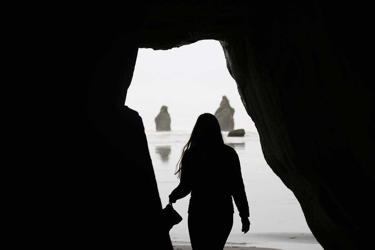 nature silhouette of woman near the cave shoreline