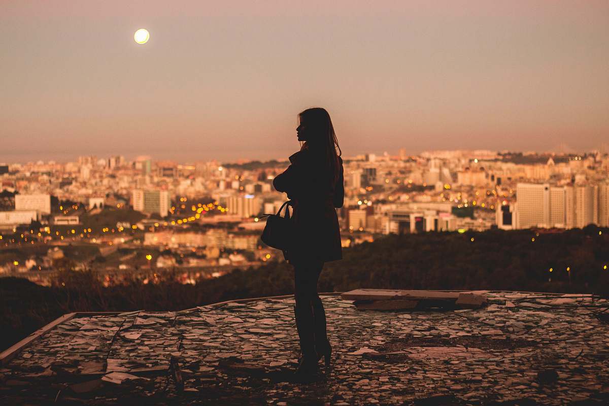 person silhouette of woman standing during golden hour photography lisbon