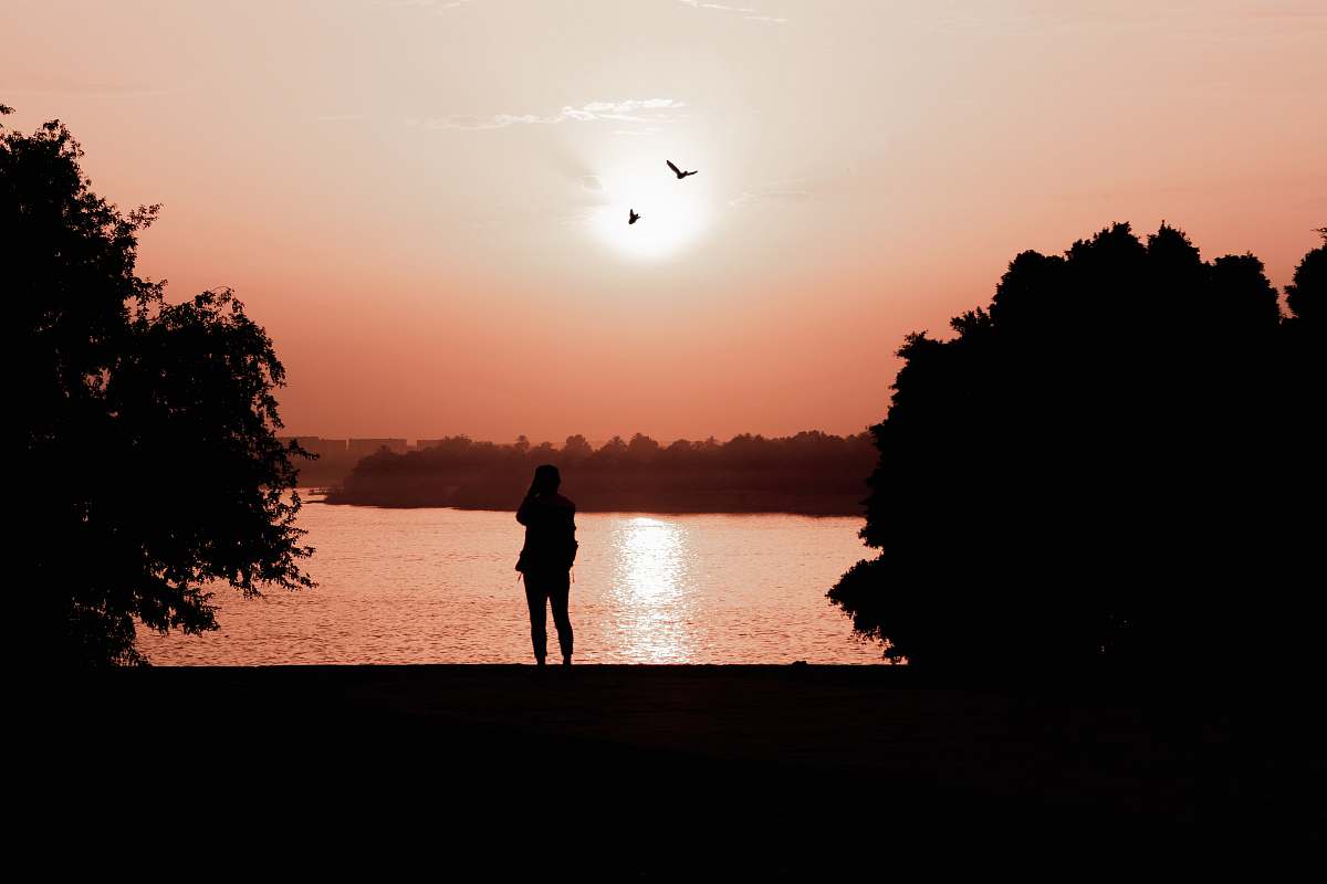 human silhouette of woman standing near body of water person