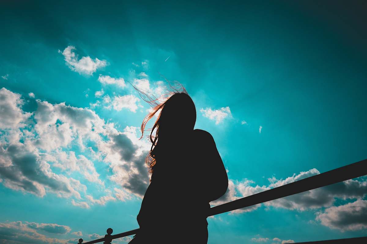sky silhouette of woman standing with cloudy sky blue