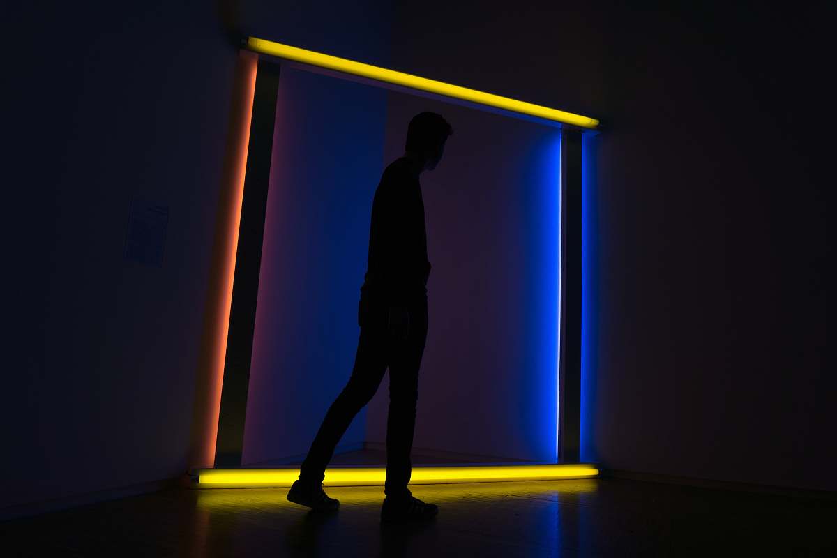 neon silhouette on man standing on lighted wall art