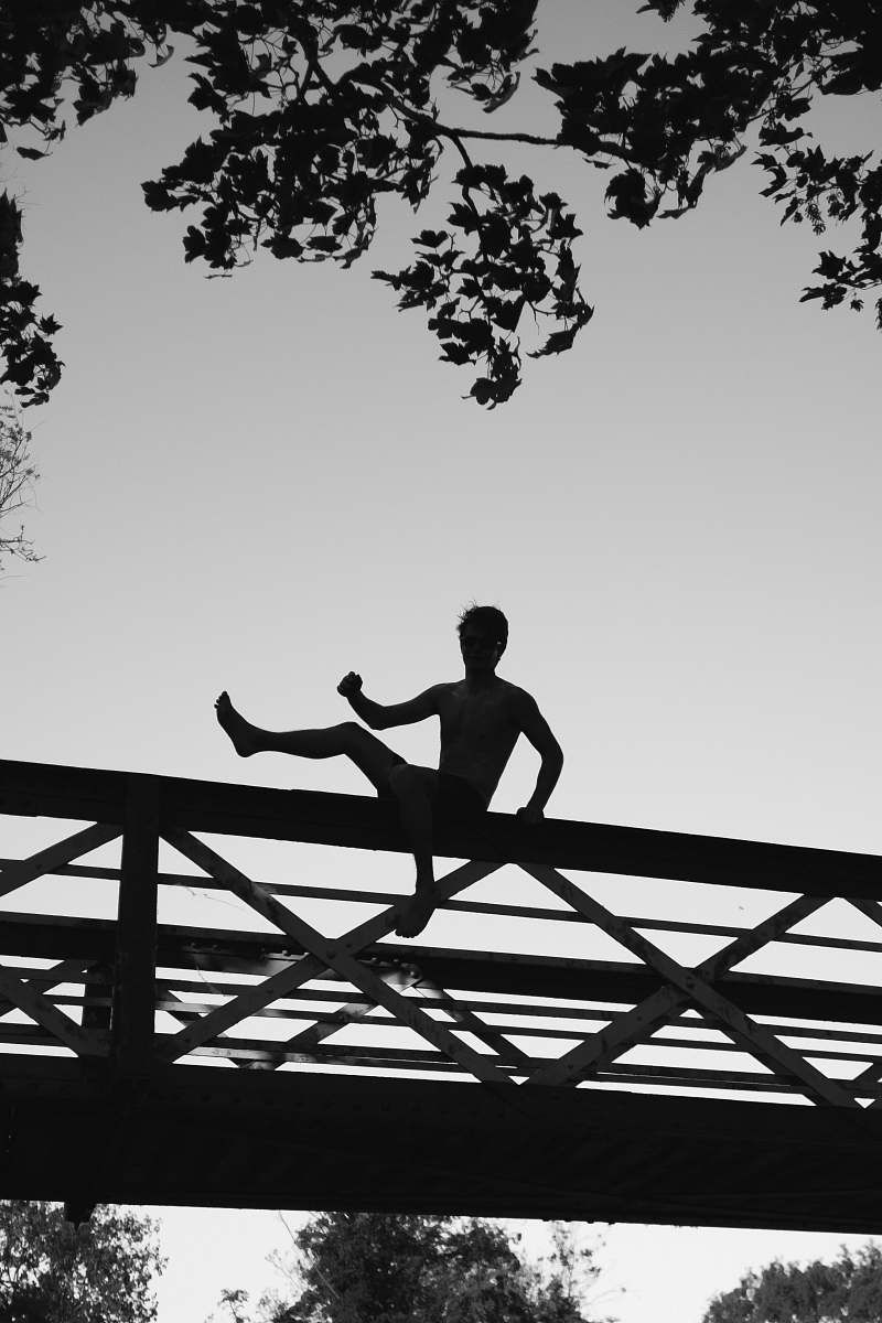 black-and-white silhouette photo of a man about to jump on footbridge cambridge