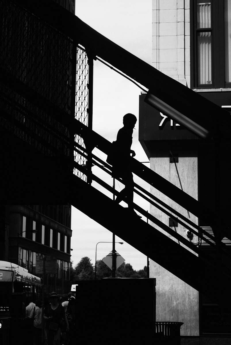 person silhouette photo of a person walking down on stair black-and-white