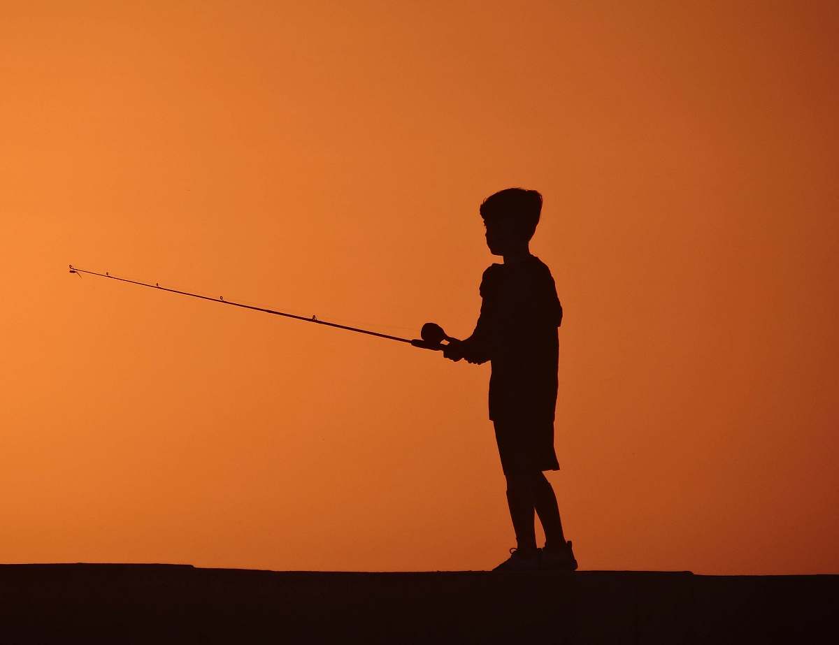 human silhouette photo of boy fishing during sunset people
