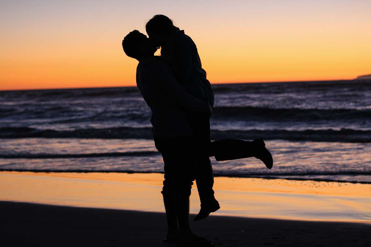 kiss silhouette photo of couple kissing near sea during golden hour love