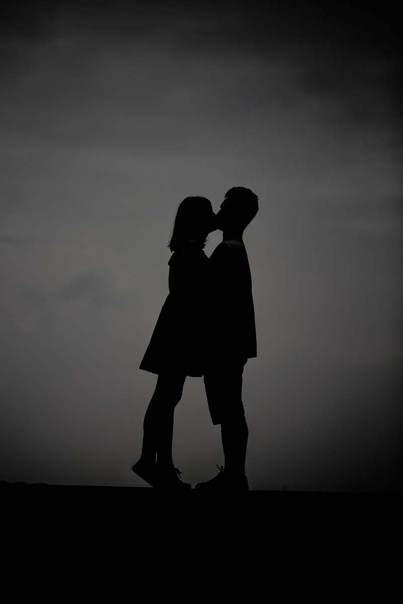 black-and-white silhouette photo of man and woman kissing grey