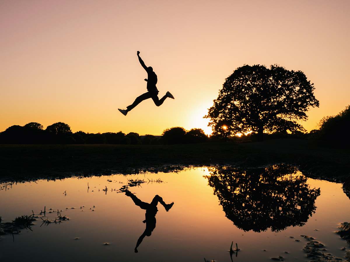london silhouette photo of man jumping on body of water during golden hour united kingdom