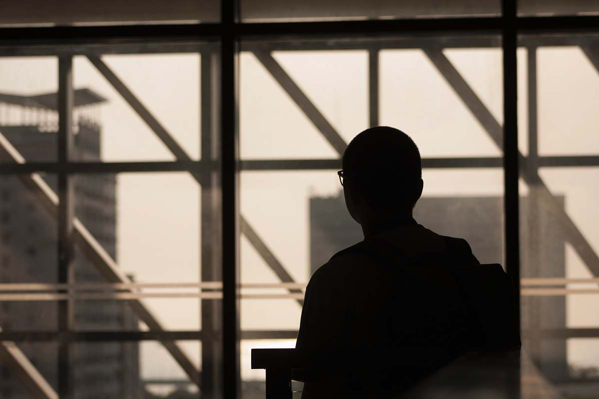 person silhouette photo of man wearing eyeglasses sitting on chair human