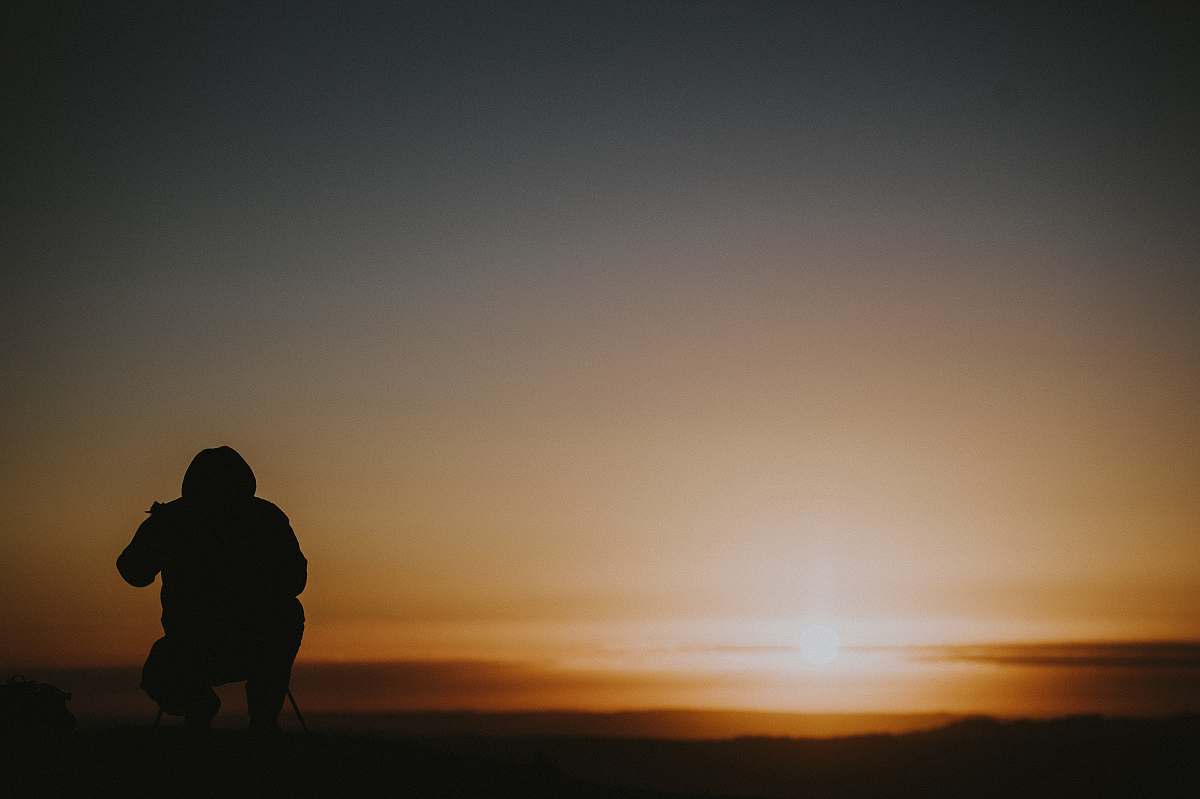 human silhouette photo of person sitting under golden hour person