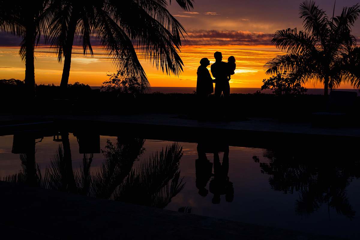 outdoors silhouette photo of three person near body of water during sunset sunset