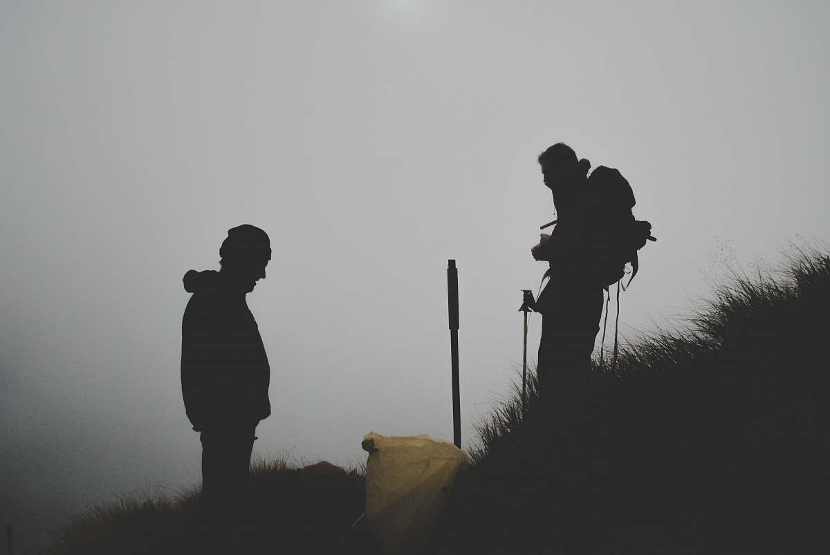 human silhouette photo of two men climbing mountain people
