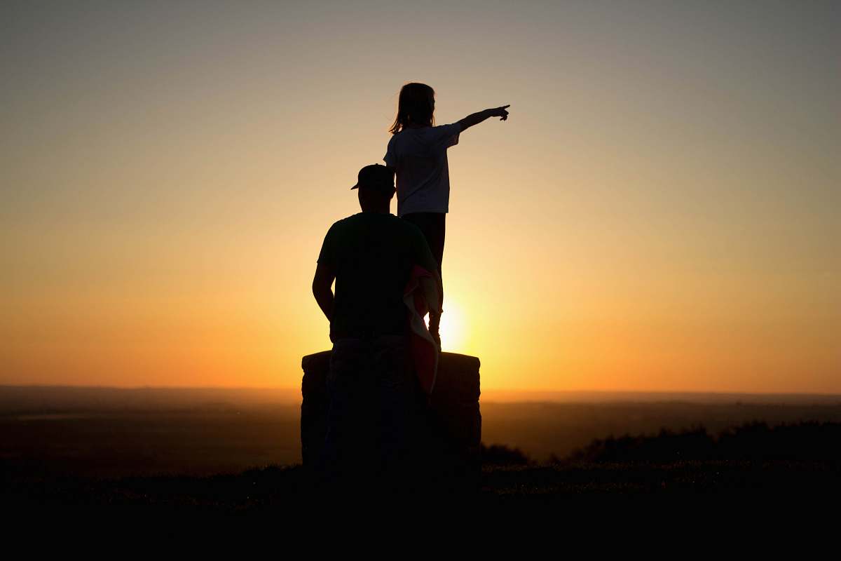 human silhouette photo of two person sitting on cliff people