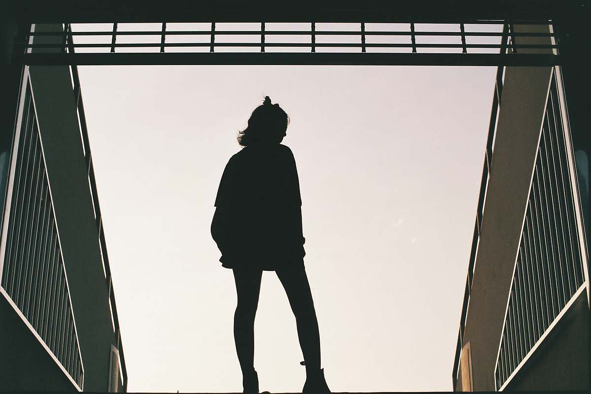human silhouette photo of woman standing on concrete road people