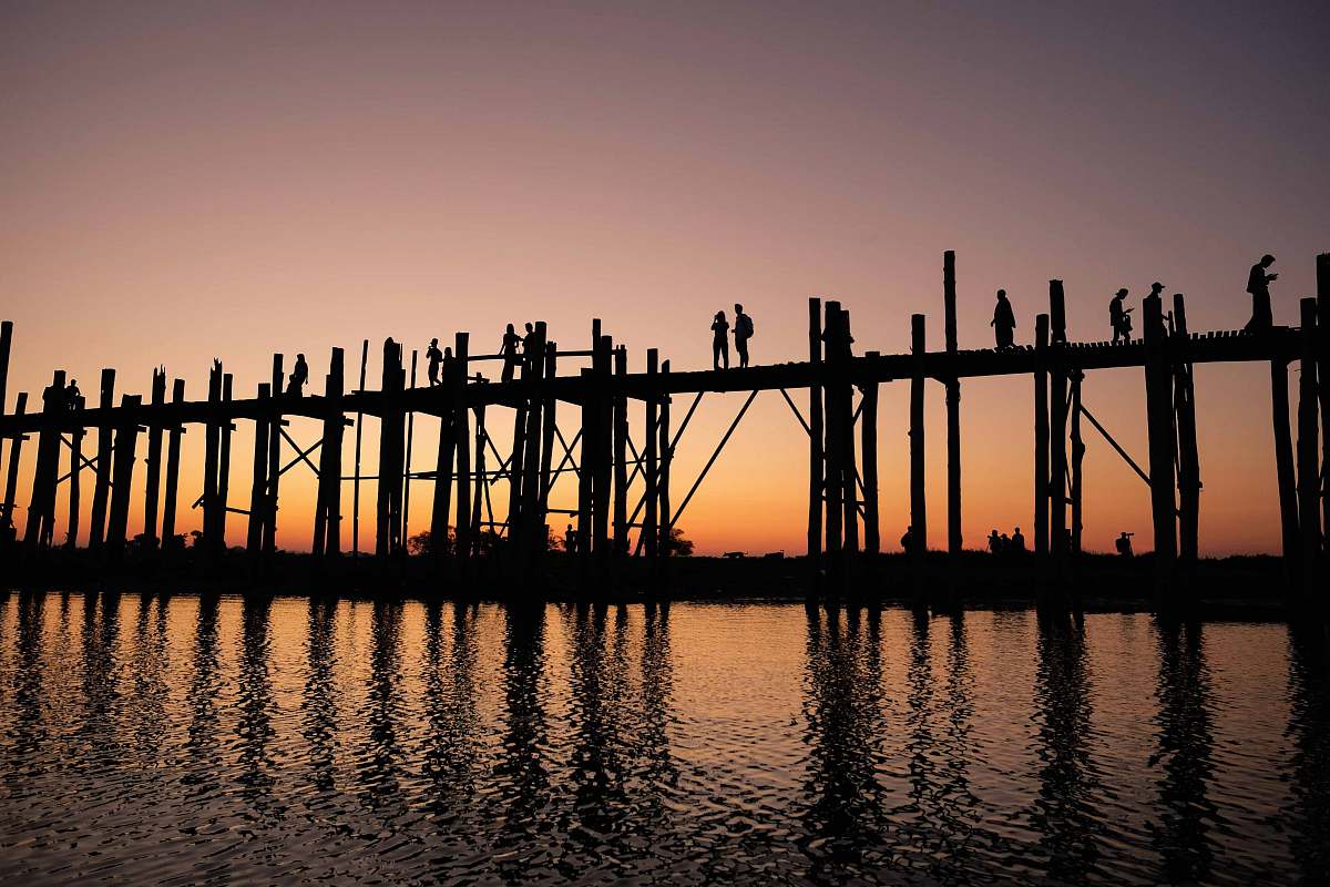pier silhouette photograph of two person standing on wooden bridge during golden hour dock