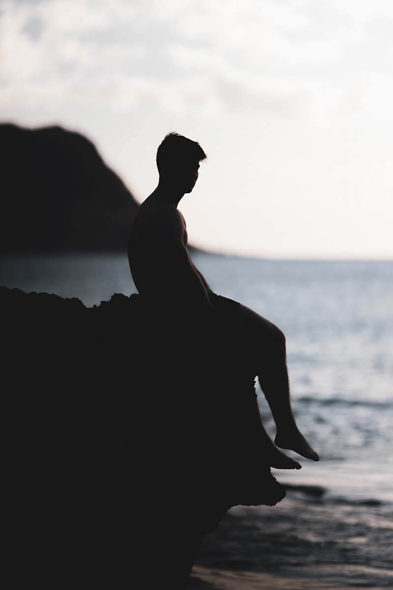 human silhouette photography of man siting on a cliff nature