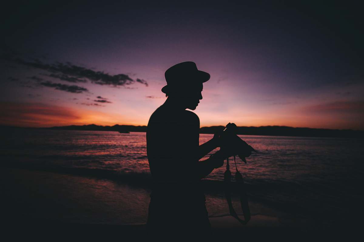 human silhouette photography of man standing while holding DSLR camera person