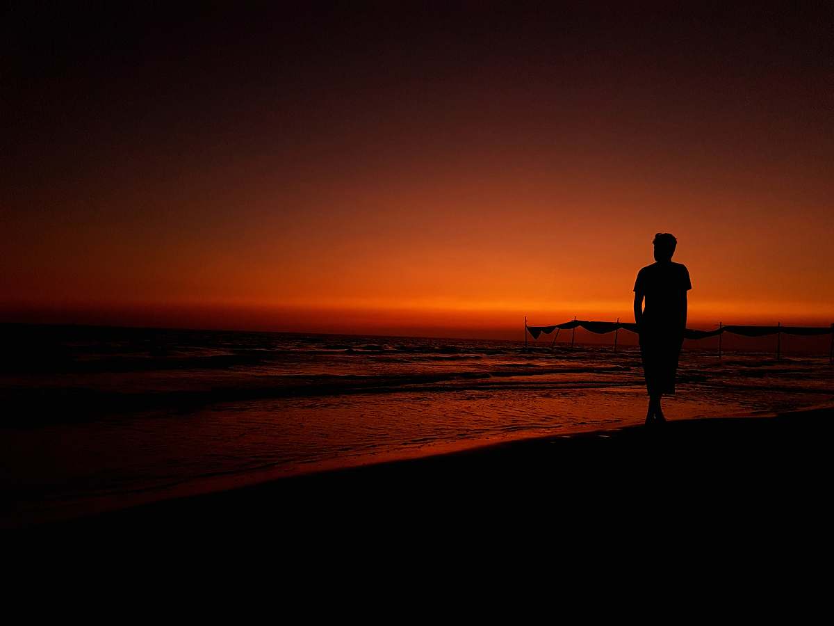 human silhouette photography of person standing on seashore person