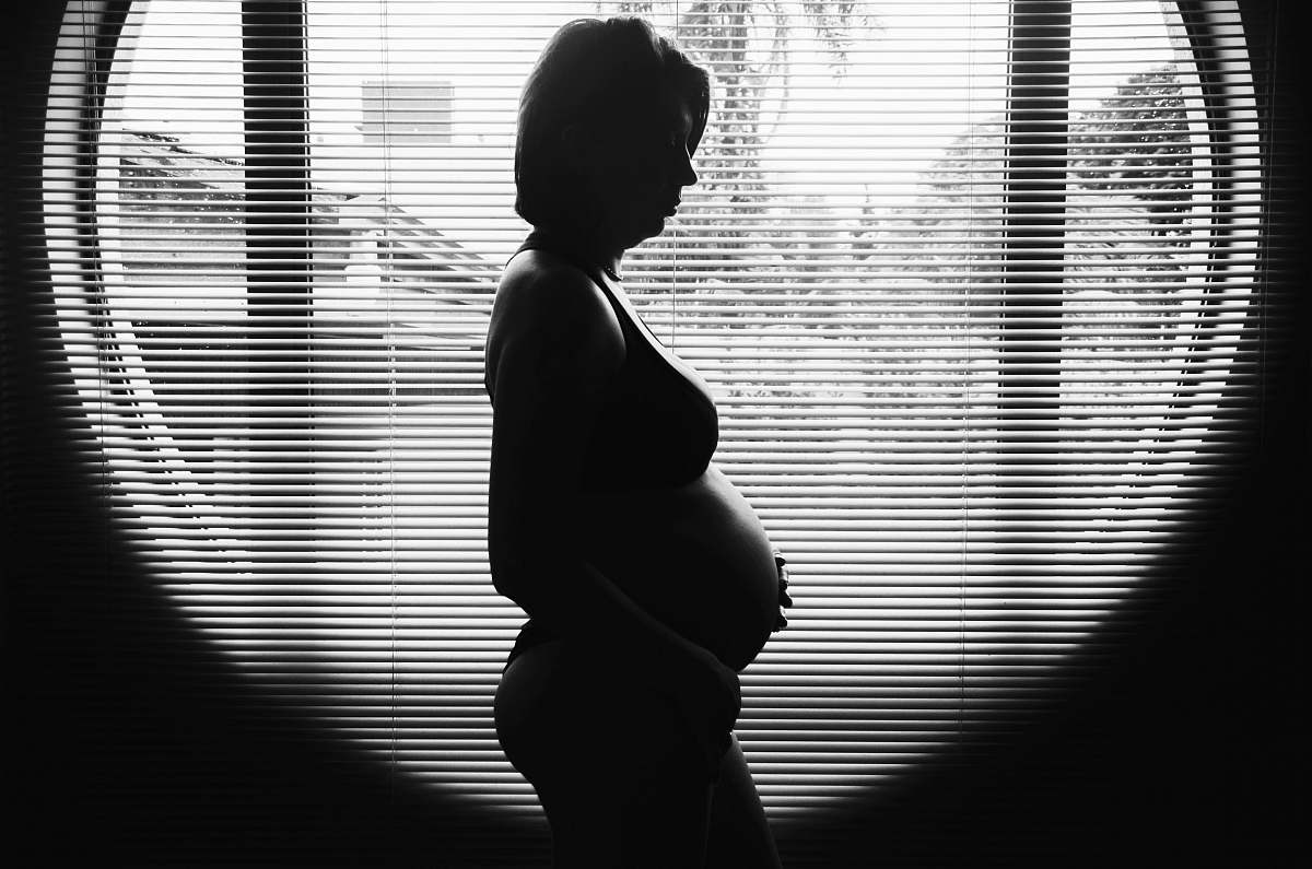 black-and-white silhouette photography of pregnant woman near window black & white